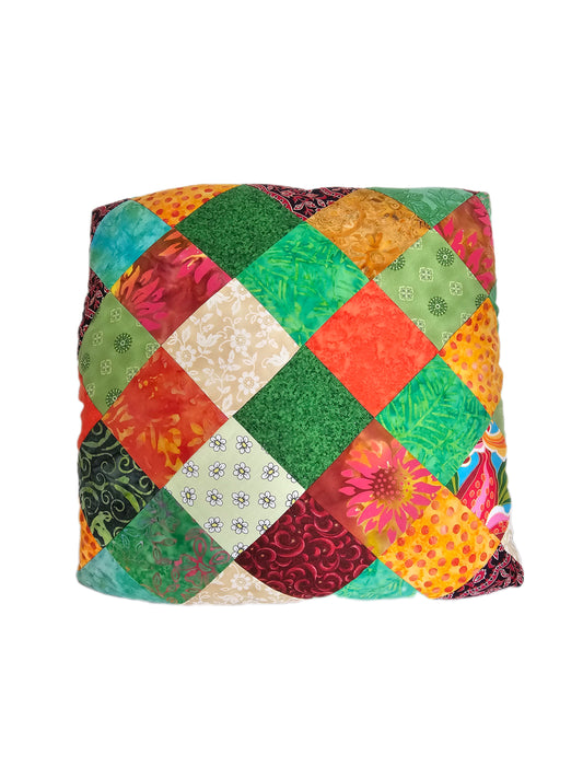 Multicoloured patchwork cotton fabric gift wrap with small patterned squares in green, orange, red, cream and turquoise on a white background