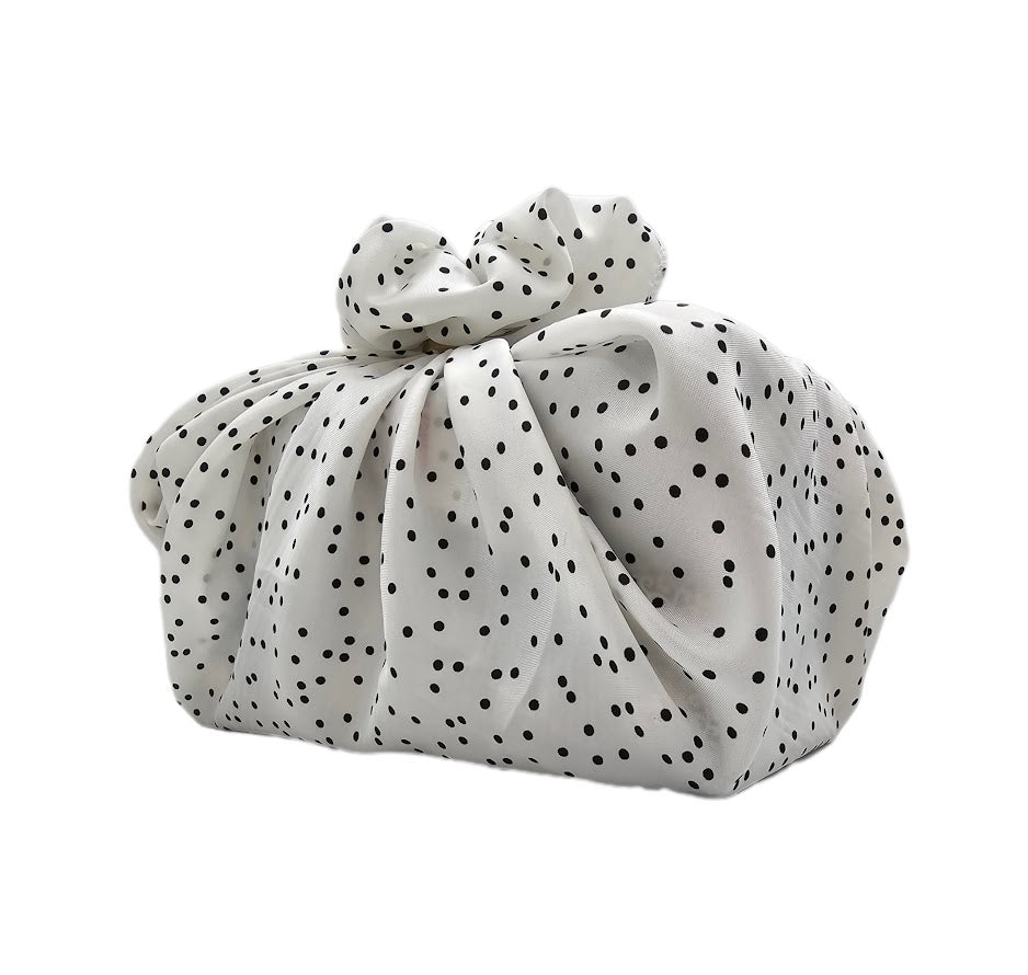 White reusable fabric gift wrap with black pattern tied around a box-shaped gift