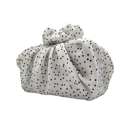 White reusable fabric gift wrap with black pattern tied around a box-shaped gift
