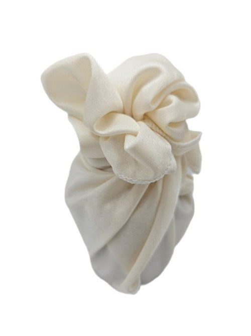 Small gift wrapped in cream polyester fabric with a soft draped knot and white overlocked edging