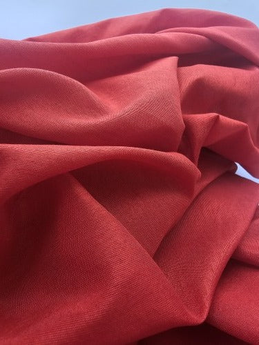 Close-up of vivid red textured polyester fabric showing its slightly open weave and structured surface