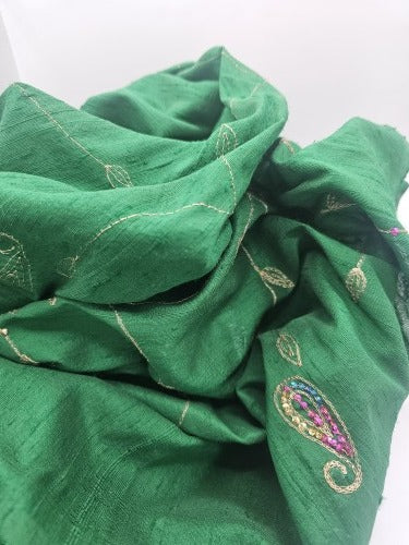 Draped emerald green raw silk showing gold-coloured embroidered leaves, multicoloured sequin detail and the fabric’s natural textured surface