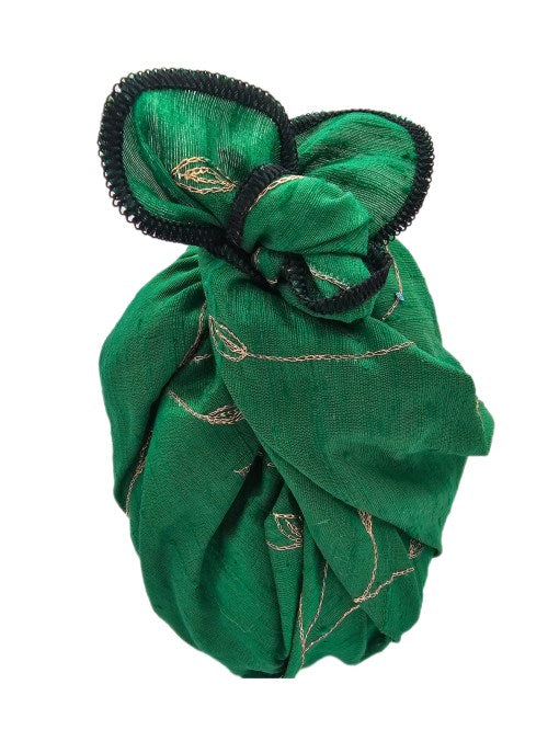 Gift wrapped in emerald green raw silk with gold-coloured vine-and-leaf embroidery, multicoloured sequins and black overlocked edging, tied in a structured knot