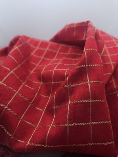 Close-up of red raw silk showing its textured grain and firm raised gold-coloured lattice embroidery