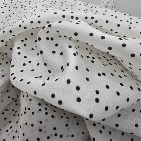 Close-up of Polka Wrap reusable fabric gift wrap showing silky white fabric with black polka dots.