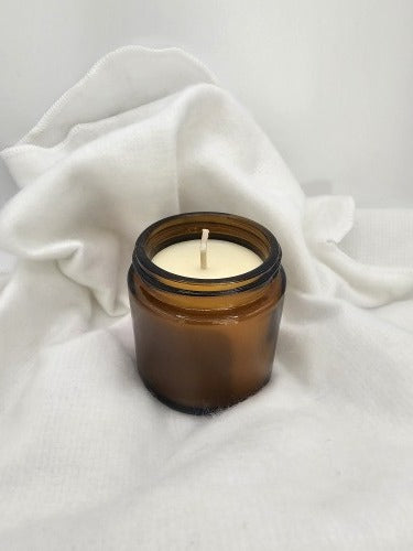 Amber glass candle placed on white Protector Wrap fabric, showing how it cushions a delicate gift before wrapping.
