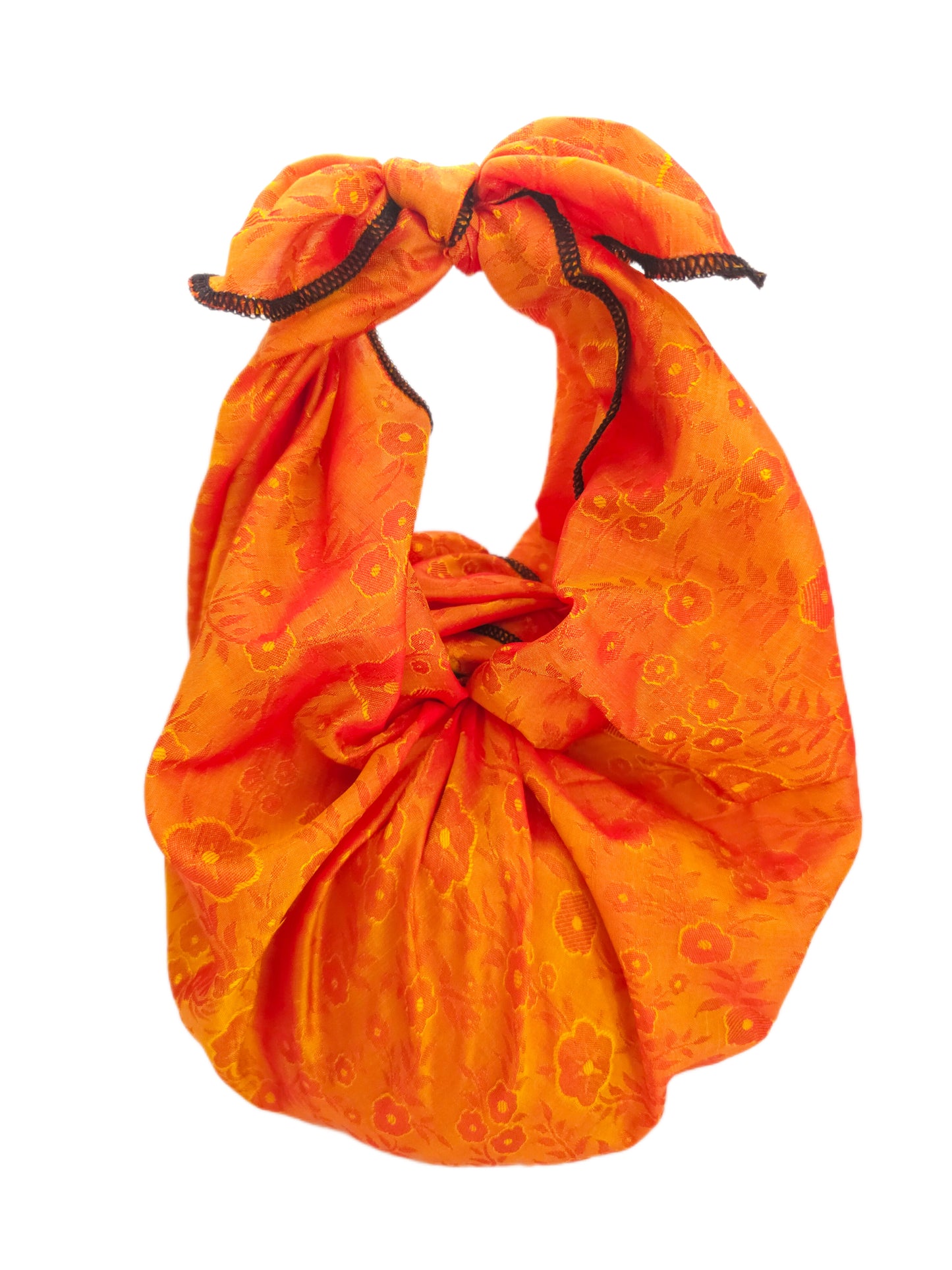 Gift wrapped in iridescent orange silk with woven flower and leaf motifs, tied with full rounded folds and contrasting black overlocked edging