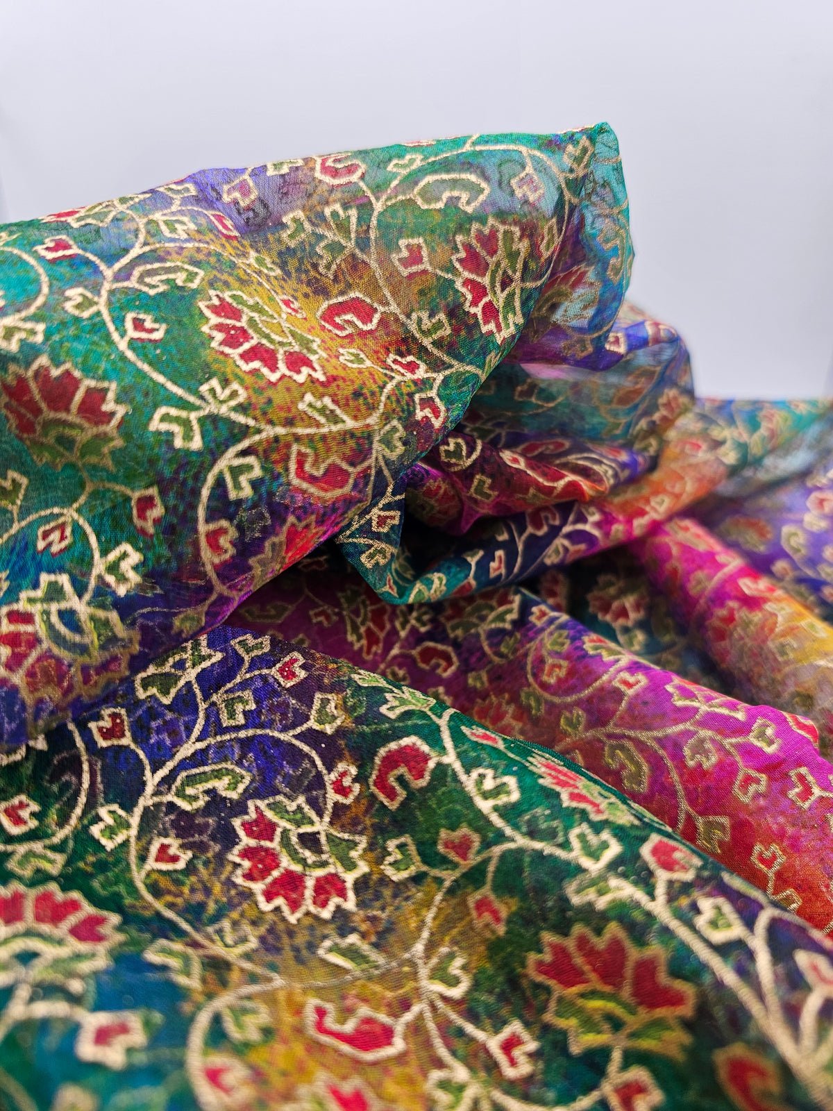 Close-up of Rainbow Gold reusable fabric gift wrap showing a multicoloured leaf and floral pattern with gold detailing.