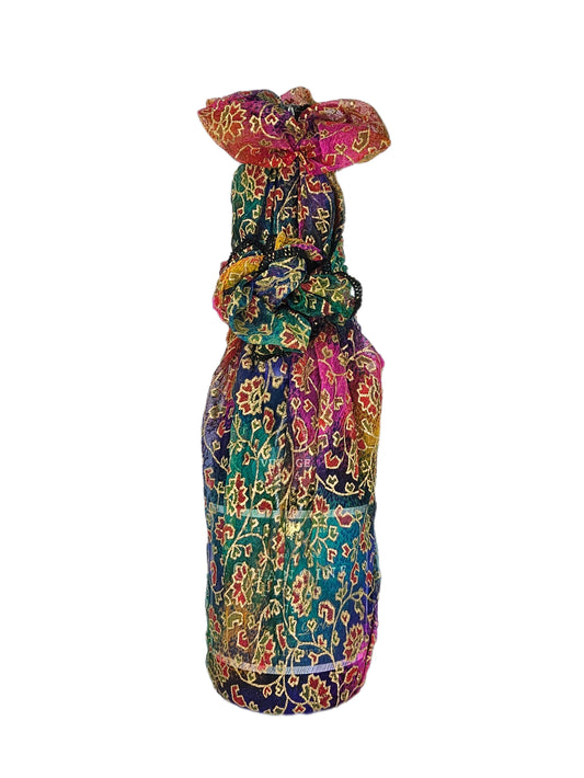 Rainbow Gold reusable fabric gift wrap tied around a bottle, showing the colourful leaf and floral print with gold detailing.