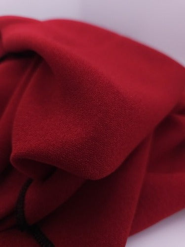Close-up of vivid red polycotton fabric showing its lightly textured weave, soft surface and black overlocked edge