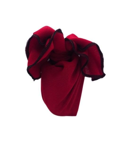Small gift wrapped in vivid red polycotton fabric, tied at the top with softer relaxed ends and contrasting black overlocked edging