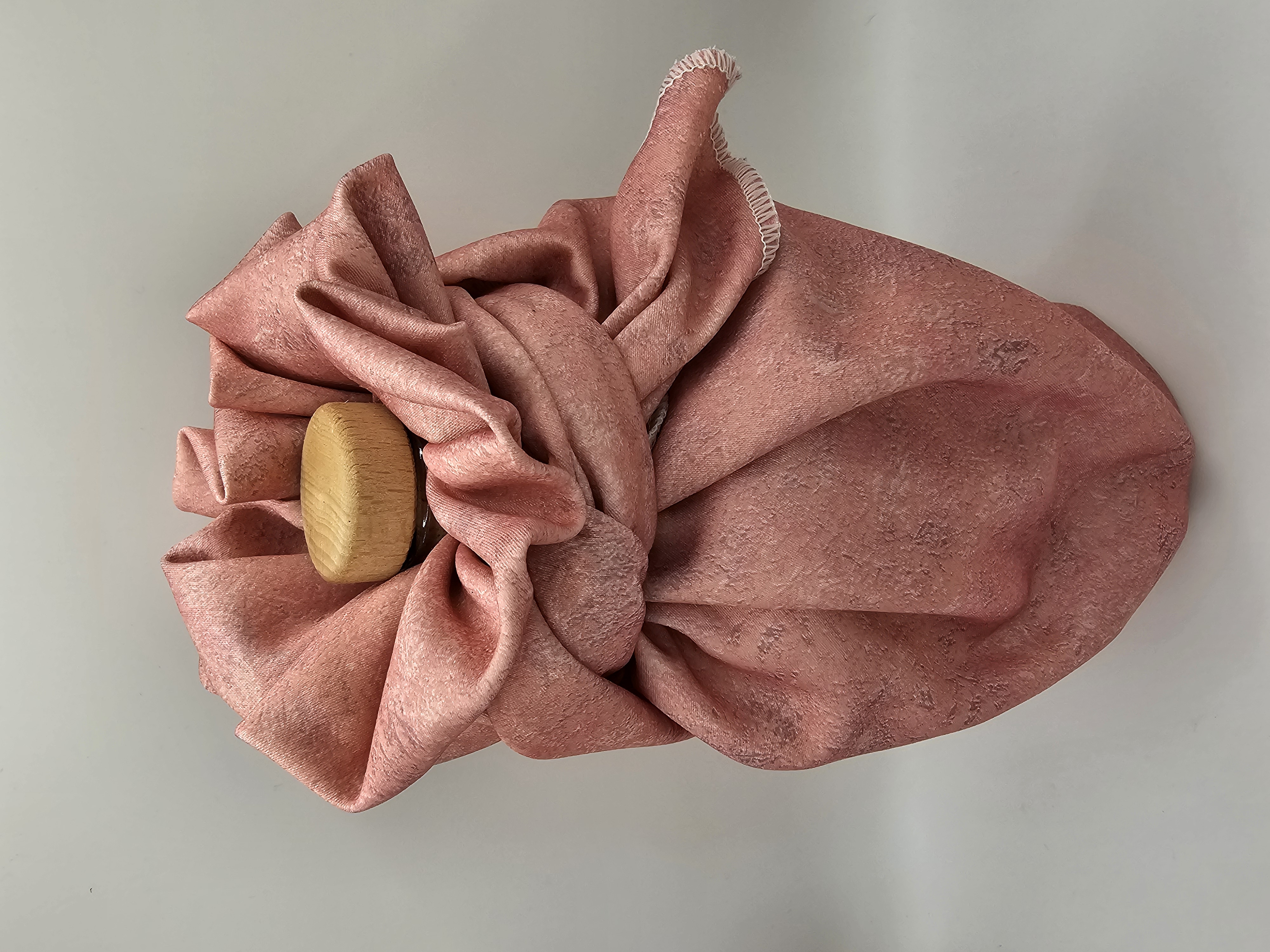 Bottle_wrapped_in_pink_gift_wrapping_fabric_tied_with_fancy_bow_with_wooden_bottle_lid_showing_at_the_top_image