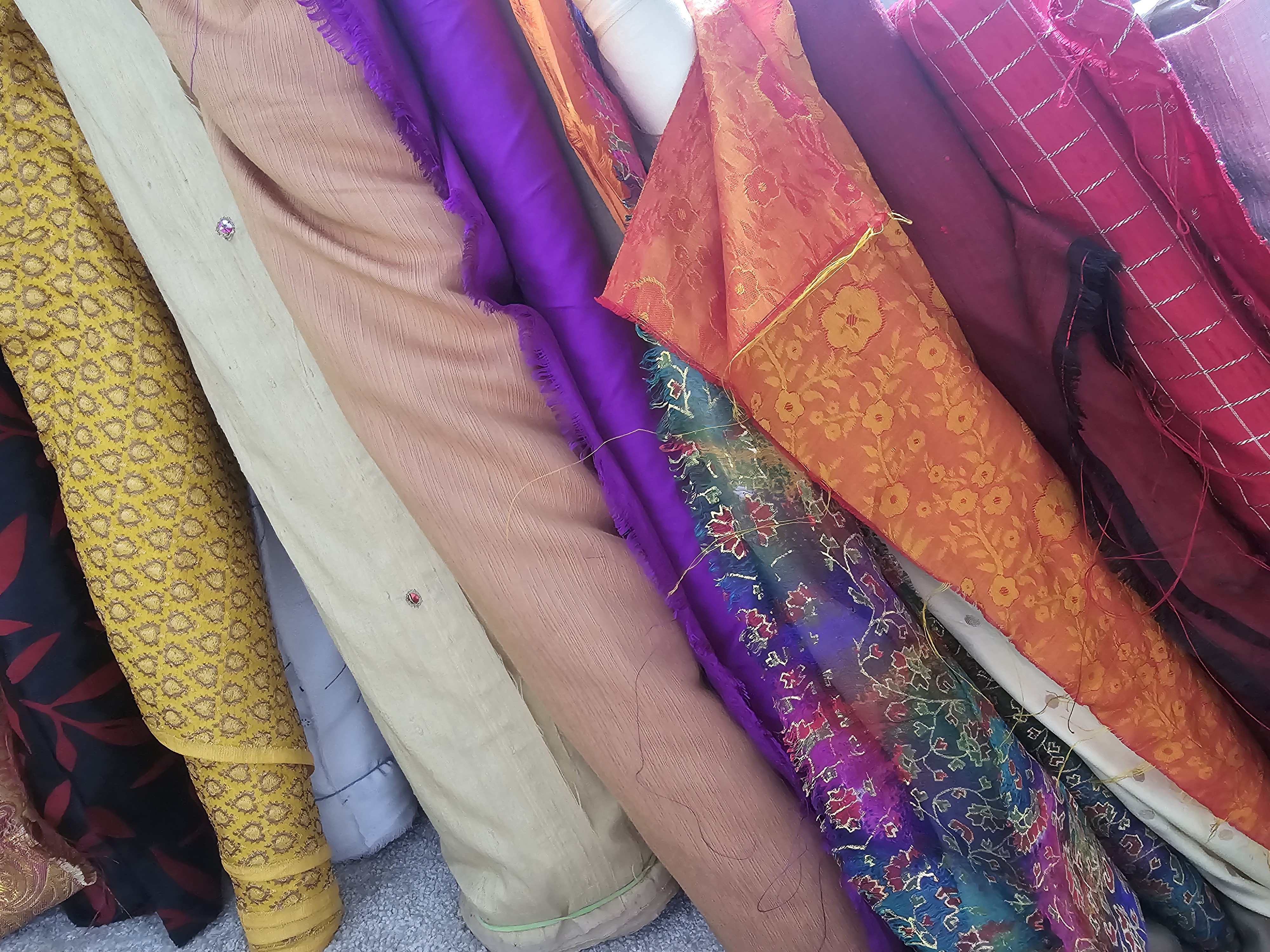 An image with lots of brightly coloured patterned and plain fabrics lined up together