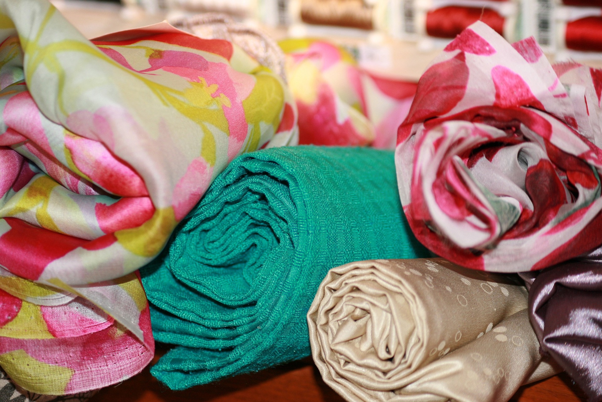 Image with coloured and patterned fabric rolled up and piled untidily next to each other