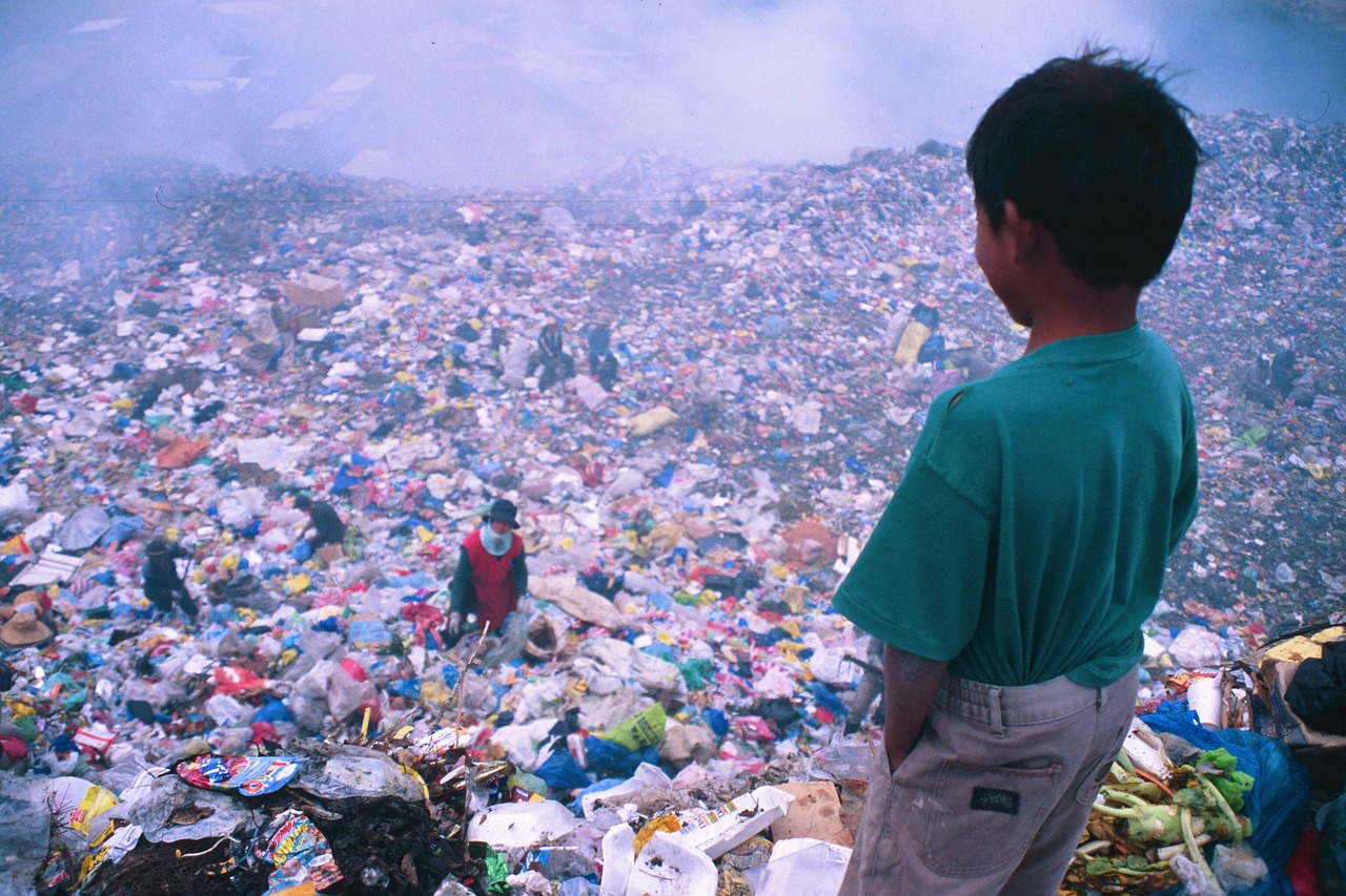 Image of boy looking down onto landfill dump site at all the rubbish 