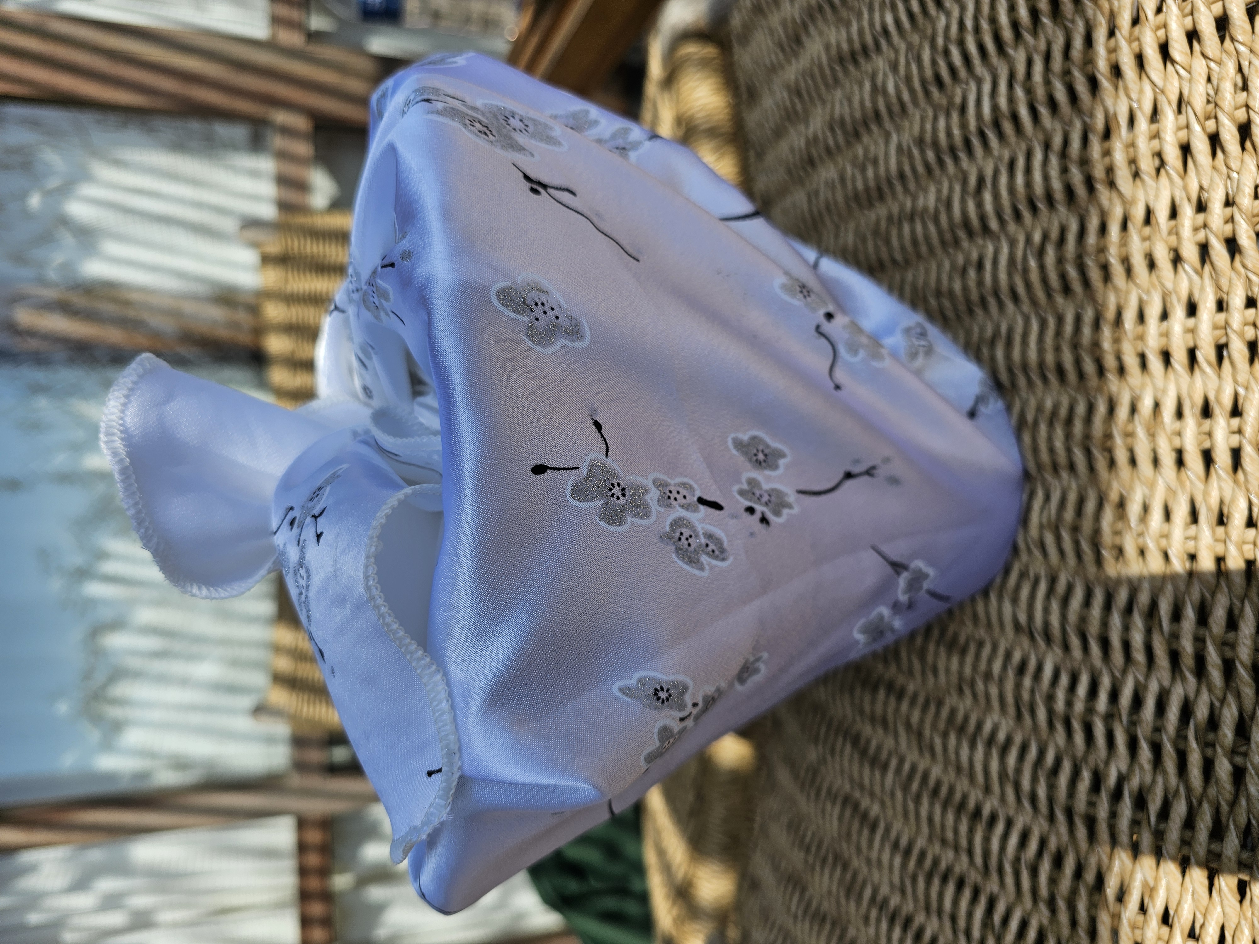 white fabric wrapping with silver and black cherry blossom design wrapping an empty plant pot outside in the sunshine